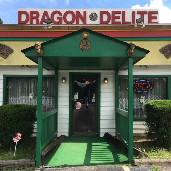 Exterior of Dragon Delite restaurant with a green entrance canopy and an "OPEN" sign in the window.